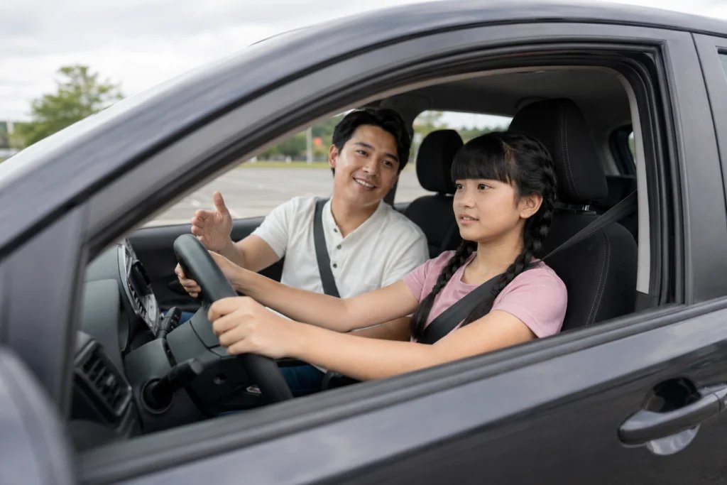Father instructing his teenage daughter during a driving lesson in a parked car