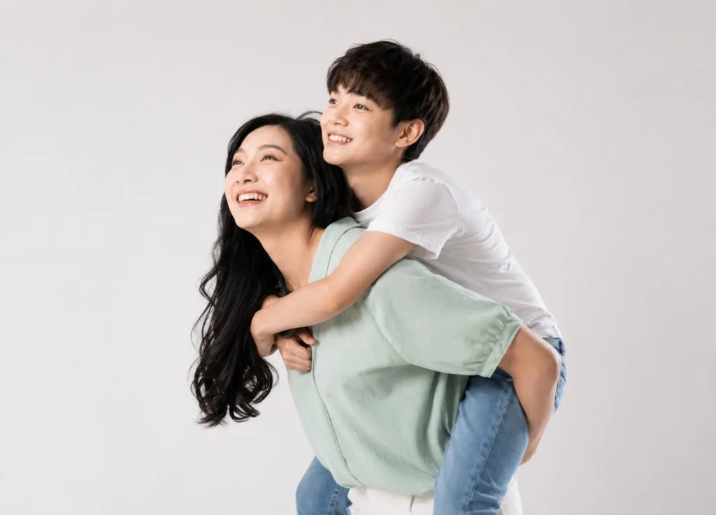 Present-day mother and adult son recreating the pose of an old childhood photo