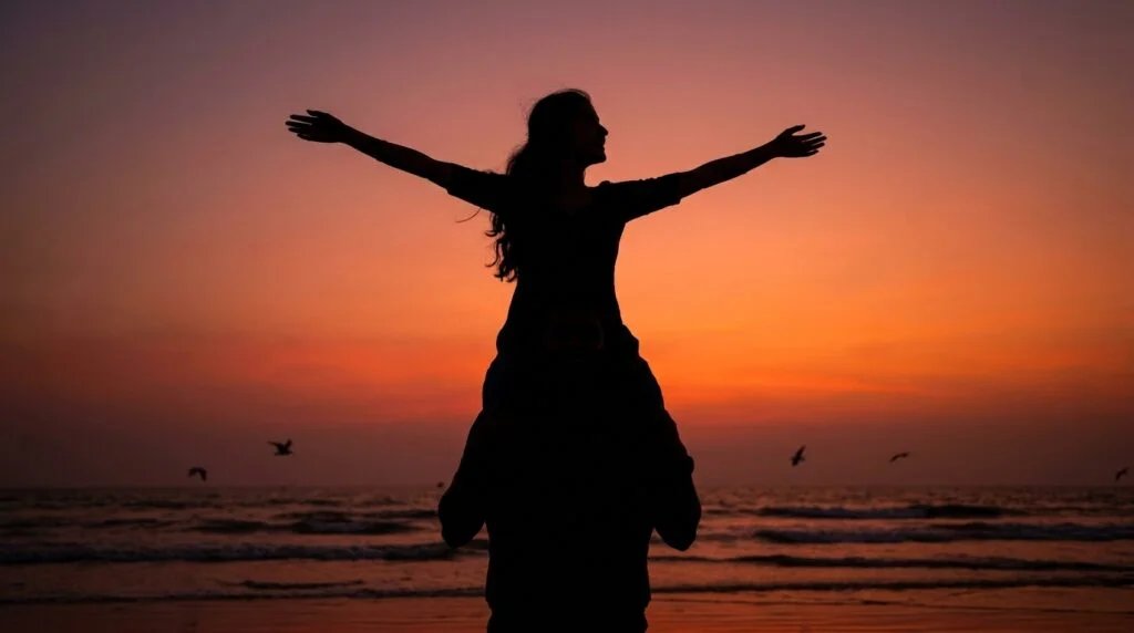 Playful romantic couple in silhouette on a beach at sunset