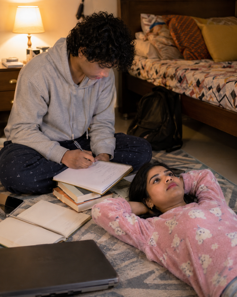 Teenage brother and sister studying together on a bedroom floor