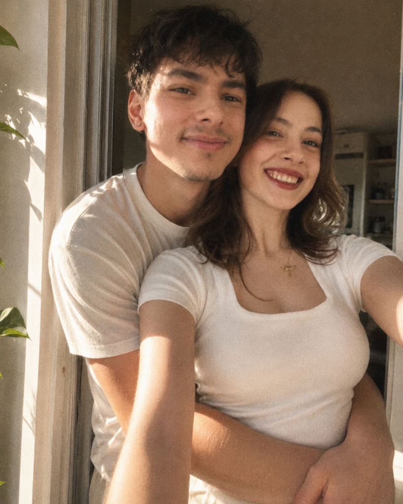 Couple sharing a candid back hug in a sunlit doorway with soft film grain