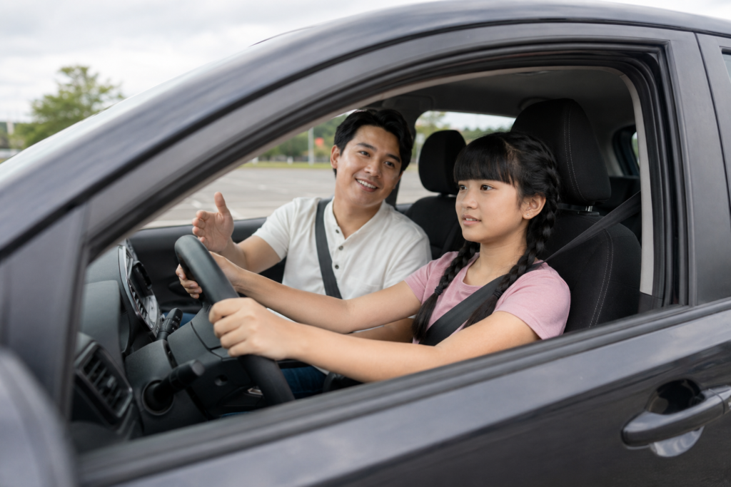 Father instructing his teenage daughter during a driving lesson in a parked car