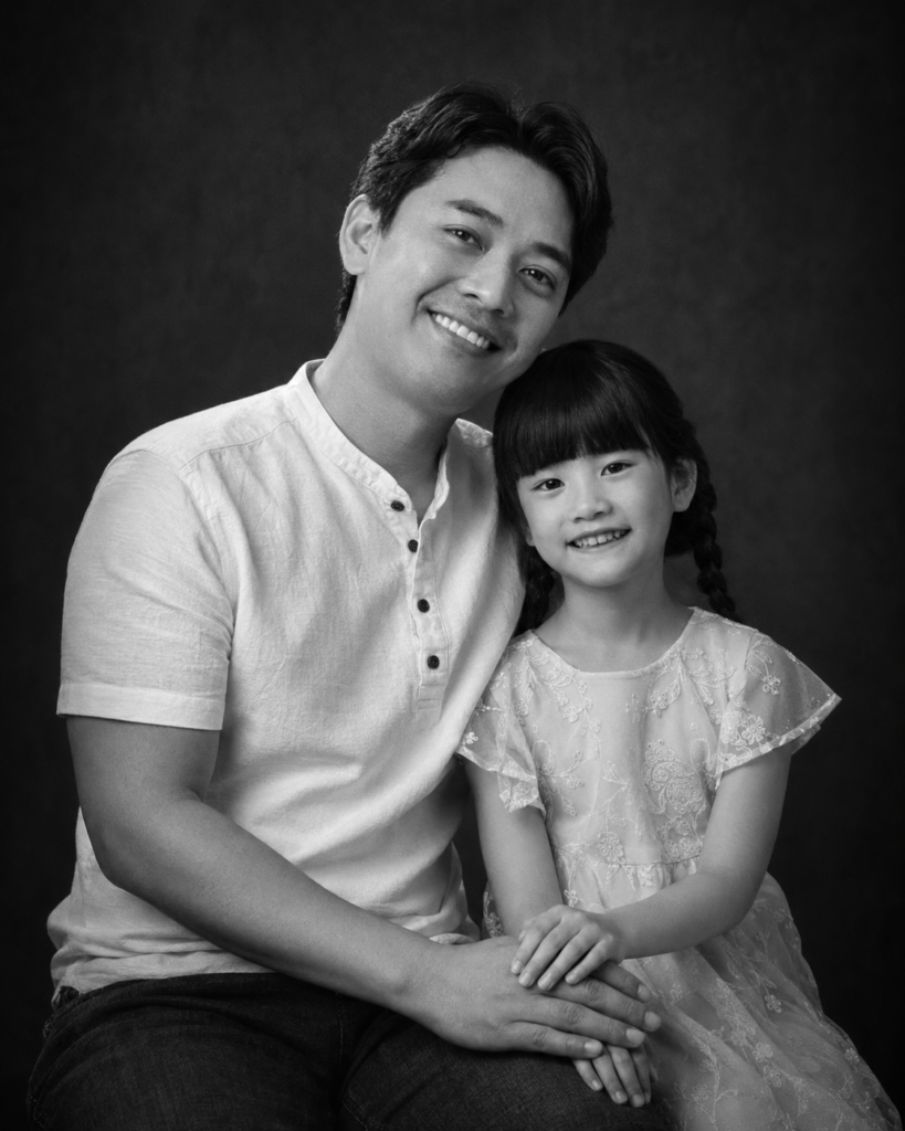 Fine-art black and white portrait of a father and daughter with their hands visible