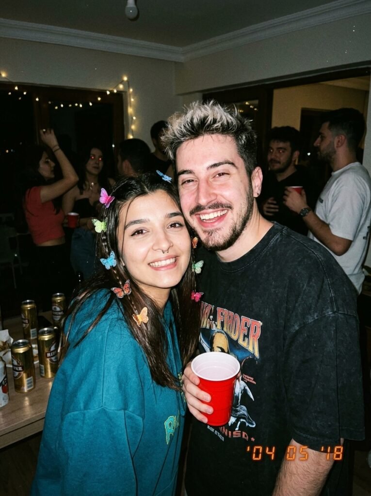 Couple at a house party photographed with harsh Y2K disposable-camera flash