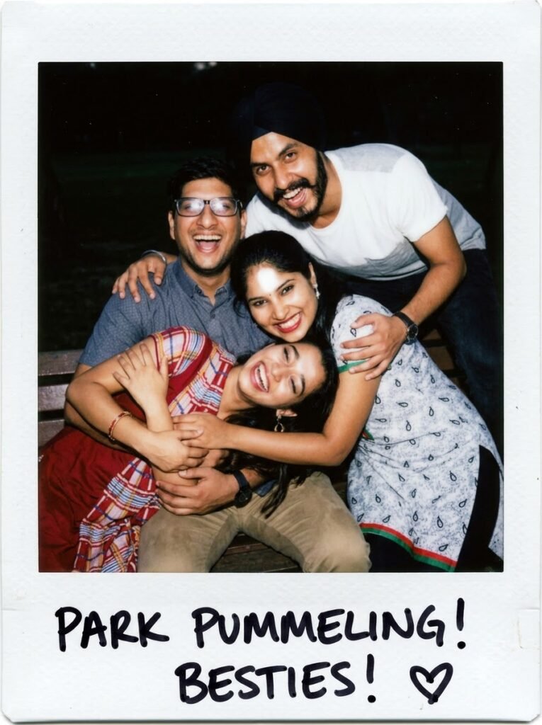 Four friends laughing together in a candid Polaroid-style group photo