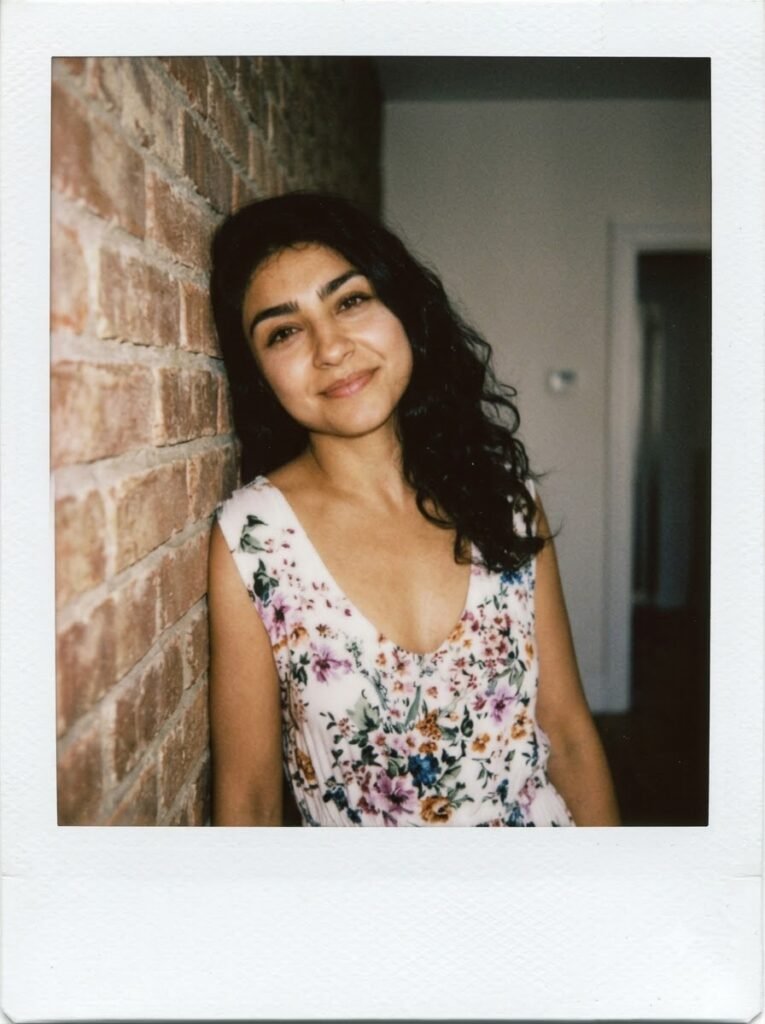Woman leaning against a wall in a warm Polaroid-style portrait